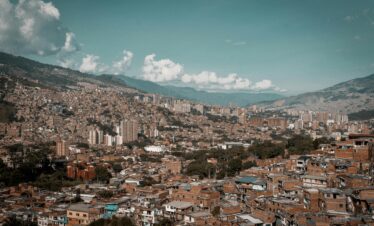 A panoramic aerial view of Medellín, showcasing its dense urban landscape against a backdrop of mountains.