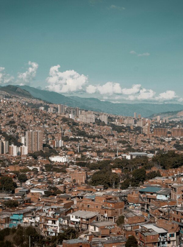 A panoramic aerial view of Medellín, showcasing its dense urban landscape against a backdrop of mountains.