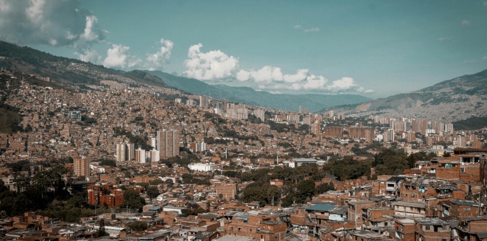 A panoramic aerial view of Medellín, showcasing its dense urban landscape against a backdrop of mountains.